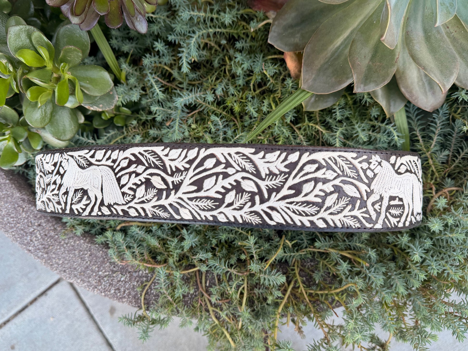 Leather belt with white floral pattern on green plants